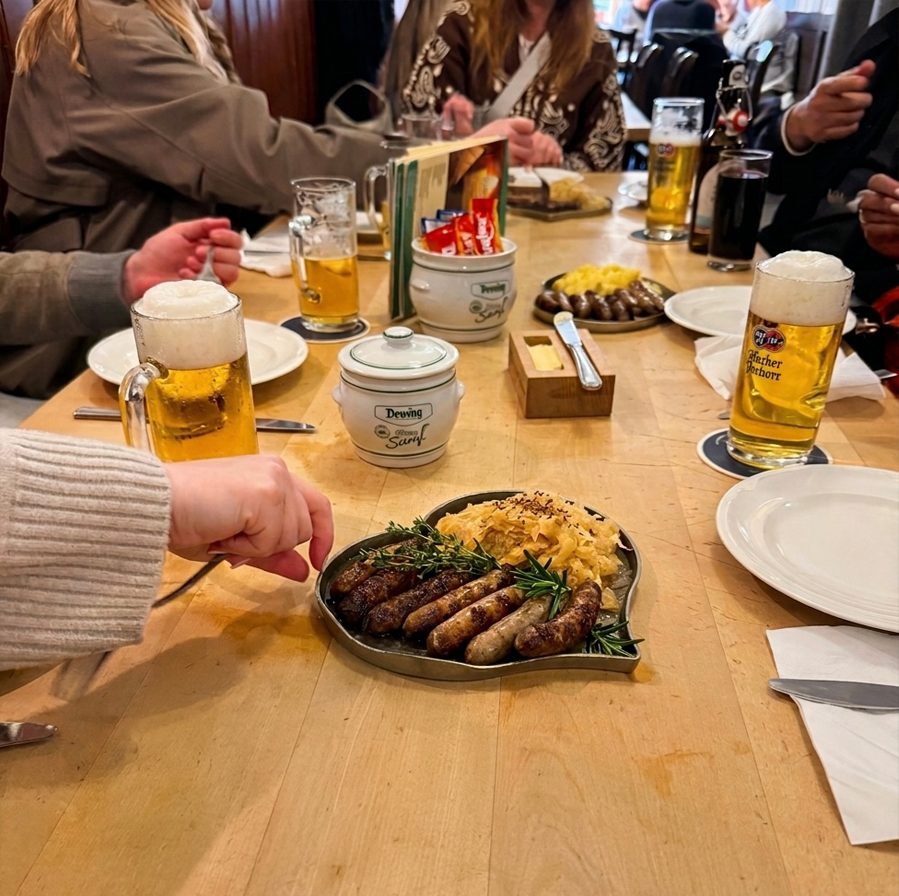 Grilled Rostbratwurst with sauerkraut and beers on a wooden table.